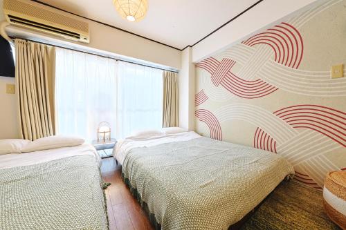 a bedroom with two beds and a window at 恵比寿駅から徒歩1分 渋谷3分 新宿10分 30m2でゆったり 最高の立地 302号室 in Tokyo
