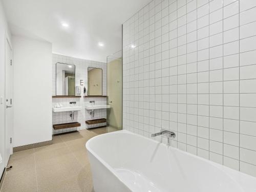 a white bathroom with a tub and two sinks at Mercure Pakenham in Pakenham