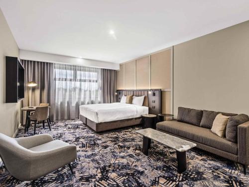a hotel room with a bed and a couch at Mercure Pakenham in Pakenham