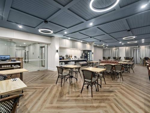 a restaurant with tables and chairs in a room at Mercure Pakenham in Pakenham