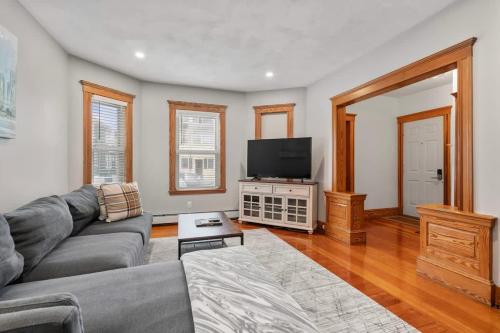 Una sala de estar con un sofá y un televisor de pantalla plana. en Tufts 2 Bed & Office - Free Parking, en Medford
