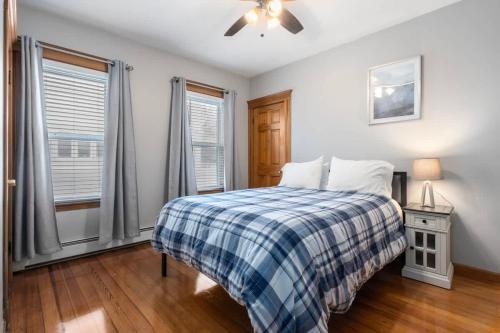een slaapkamer met een bed met een geruite deken en 2 ramen bij Tufts 2 Bed & Office - Free Parking in Medford