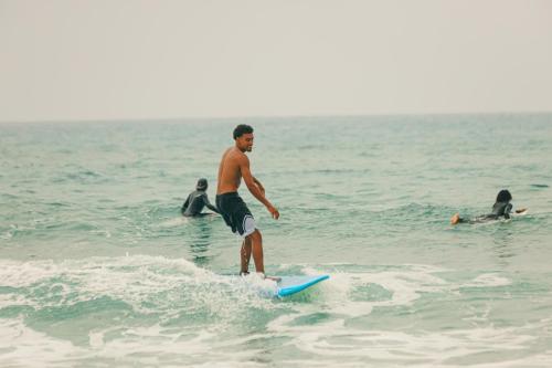 a man riding a wave on a surfboard in the ocean at Surfer's Heimat Hostel in Tamraght Ouzdar