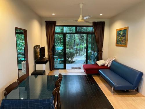 een woonkamer met een blauwe bank en een glazen tafel bij The Wild Villa Phuket Rawai in Nai Harn Beach