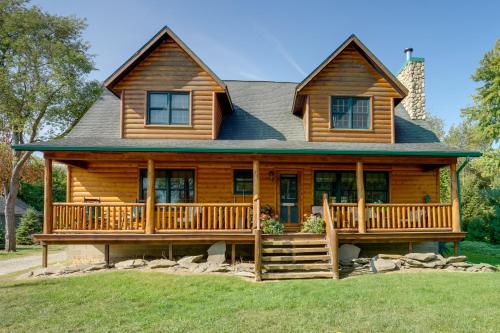 a log home with a large porch and deck at 1 Mi to Public Beach Port Austin Cabin with Hot Tub in Grind Stone City