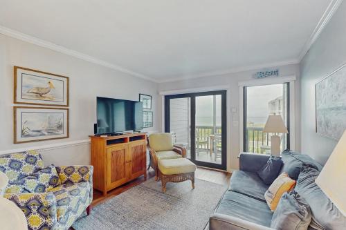 a living room with a couch and a tv at Dunescape Villas 211 in Atlantic Beach