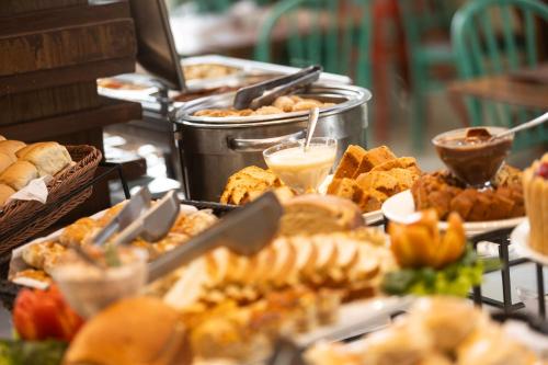 a buffet filled with different types of bread and pastries at Mais Hotel Aeroporto Salvador in Lauro de Freitas