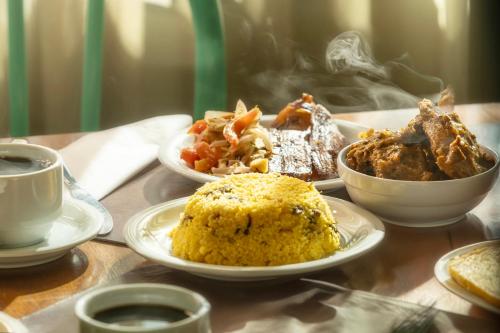 a table with plates of food and a cup of coffee at Mais Hotel Aeroporto Salvador in Lauro de Freitas