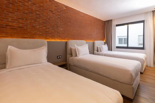 two beds in a room with a brick wall at AUREA Hotel in Tetouan