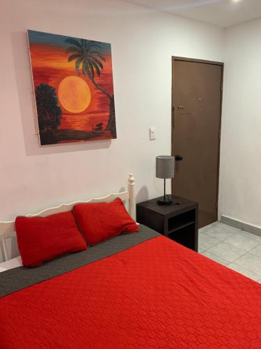 a bedroom with a red bed with a painting on the wall at Residencial Edzna in Campeche