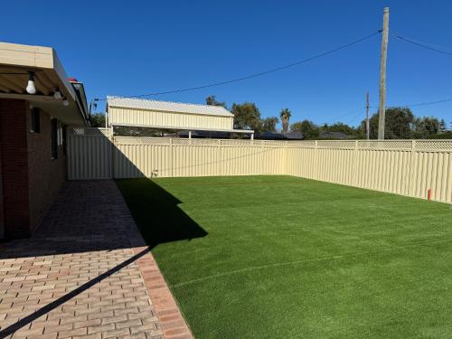 a large artificial lawn in front of a fence at Modern Stylish House in Craigie in Perth