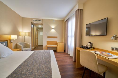 a hotel room with a bed and a desk with a television at Hotel Guadalmedina in Málaga