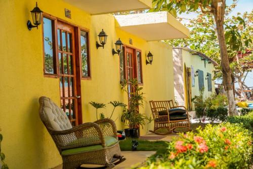 a yellow house with wicker chairs in a yard at Waikiki beach Hotel Boutique in Dibulla