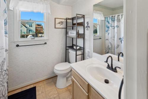 a bathroom with a sink and a toilet and a window at 6133 - Coastal Crave in Nags Head