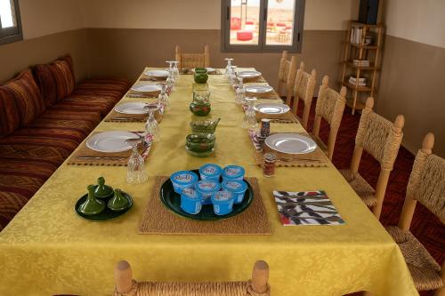 a long table with plates and blue glasses on it at Bivouac Luna in Mhamid