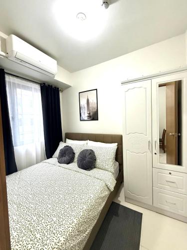 a bedroom with a bed with two pillows on it at Obetskie's Haven Condotel in Manila