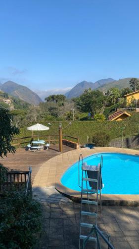 a swimming pool with a chair and an umbrella at Varanda Itaipava! in Petrópolis