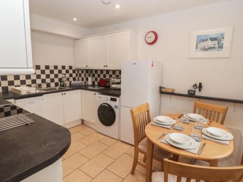 a kitchen with a table and a white refrigerator at Garth Cottage in Haverfordwest