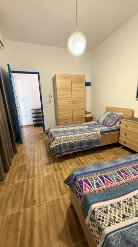 three beds in a room with wooden floors at Fairly new one bedroom guest house in Ariana