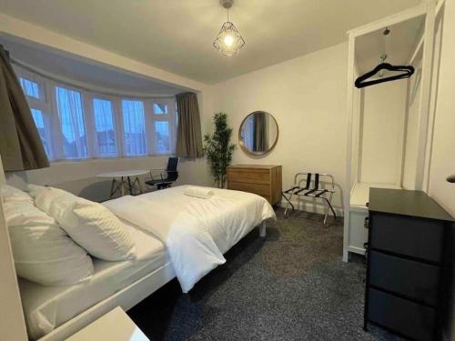 ein Schlafzimmer mit einem großen weißen Bett und einem Schreibtisch in der Unterkunft 4 Bedroom Terraced House with Huge Garden in Pinner