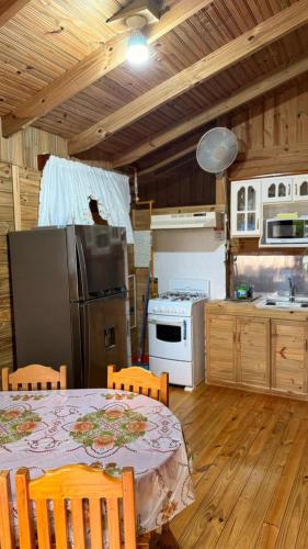 a kitchen with a table with chairs and a refrigerator at Centro Ecológico La Ribera-CABAÑA 2 in San Rafael