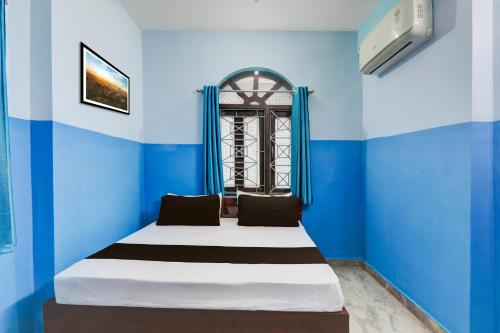a bed in a room with blue walls and a window at Hotel O Raj in Dānāpur