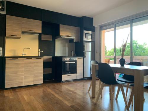 a kitchen with wooden cabinets and a table with chairs at Juan les Pins Joli T2 parking inclus! in Antibes