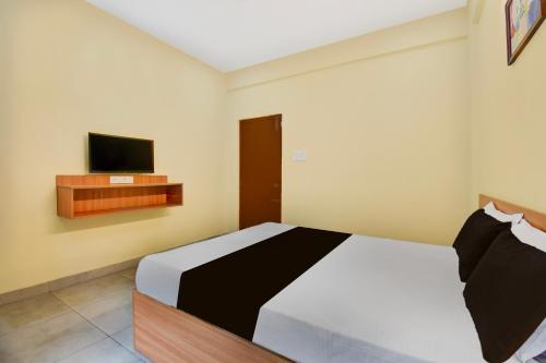 a bedroom with a bed and a flat screen tv at Hotel O MYSORE CASTLE in Belagula