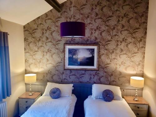two twin beds in a room with a wall at Kings Arms Hotel in Holme