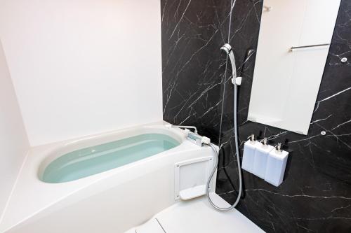 a bathroom with a bath tub and a sink at SPAZIO 6 Hakata Station in Fukuoka