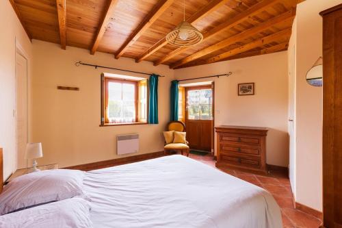 um quarto com uma grande cama branca e uma cadeira em Charmante maison au cœur d'Hengoat em Hengoat