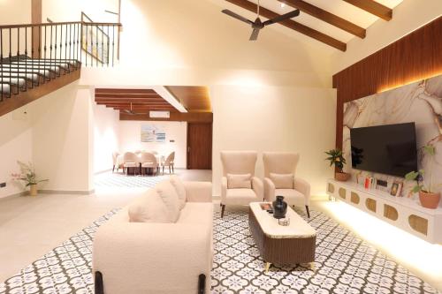 a living room with white furniture and a flat screen tv at Lamrin Morjim Goa in Morjim