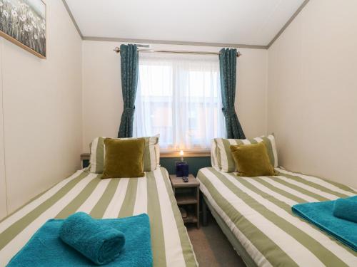 two beds in a room with a window at Sand & Serenity in Norwich