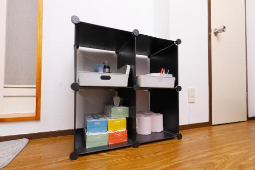 a black shelf with books and boxes in a room at 恵比寿駅から徒歩1分 渋谷3分 新宿10分 30m2でゆったり 最高の立地 403号室 in Tokyo
