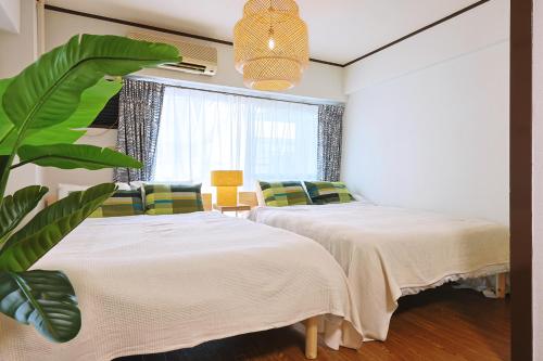 a bedroom with two beds and a plant at 恵比寿駅から徒歩1分 渋谷3分 新宿10分 30m2でゆったり 最高の立地 403号室 in Tokyo
