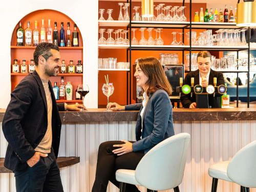 a man and a woman sitting at a bar at Mercure Dunkerque Centre Gare in Dunkerque