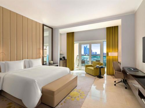 a bedroom with a large white bed and a desk at Rixos Marina Abu Dhabi in Abu Dhabi