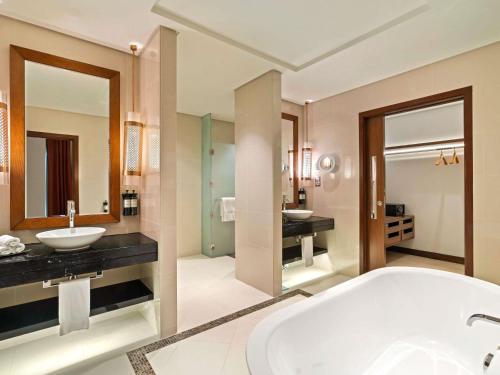 a bathroom with two sinks and a bath tub at Rixos Marina Abu Dhabi in Abu Dhabi