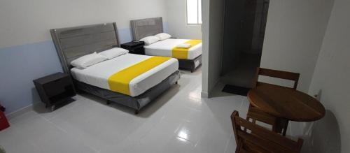 a bedroom with two beds and a table and a chair at Amaca Hostal in Santa Cruz de la Sierra
