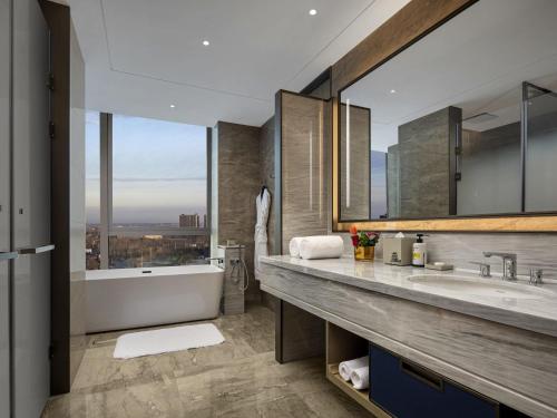 a bathroom with a tub and a large window at Pullman Huai'an in Huai'an