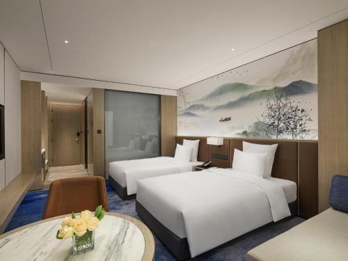 a hotel room with two beds and a table at Pullman Huai'an in Huai'an