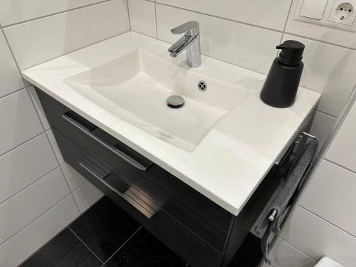 a white bathroom sink with a black soap dispenser on it at Ferienwohnung Schwalbennest in Eisfeld