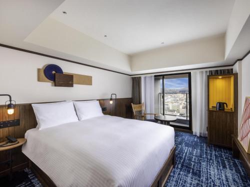 a hotel room with a bed and a large window at Mercure Hida Takayama in Takayama