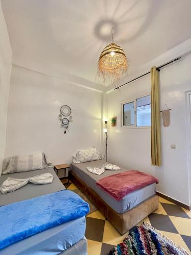 a bedroom with two beds and a chandelier at TOODA House in Imsouane