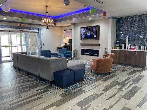 a living room with a couch and chairs and a tv at La Quinta by Wyndham Oklahoma City - Moore in Moore