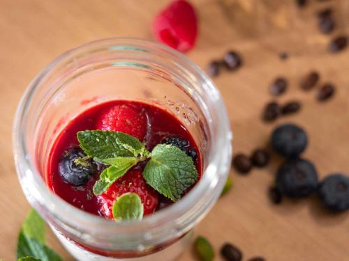 a jar of jam with berries and a green leaf on top at ibis Styles Les Houches Chamonix in Les Houches