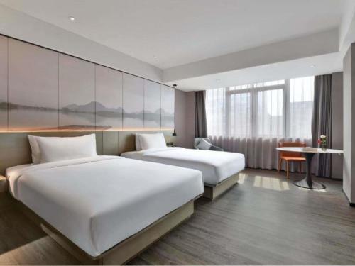 a hotel room with two beds and a desk at Mercure Guilin Hi Tech Zone in Guilin