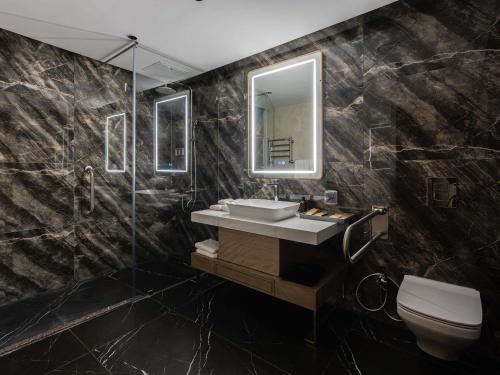 a bathroom with a sink and a mirror and a toilet at Mövenpick Samarkand in Samarkand
