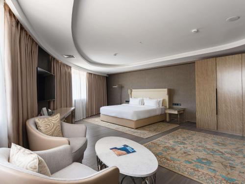 a hotel room with a bed and a couch and chairs at Mövenpick Samarkand in Samarkand