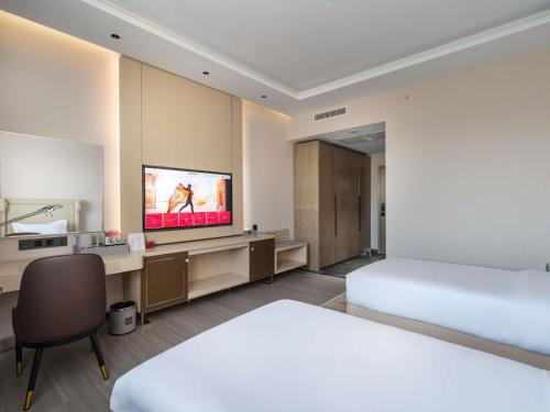 a hotel room with a bed and a flat screen tv at Mövenpick Samarkand in Samarkand